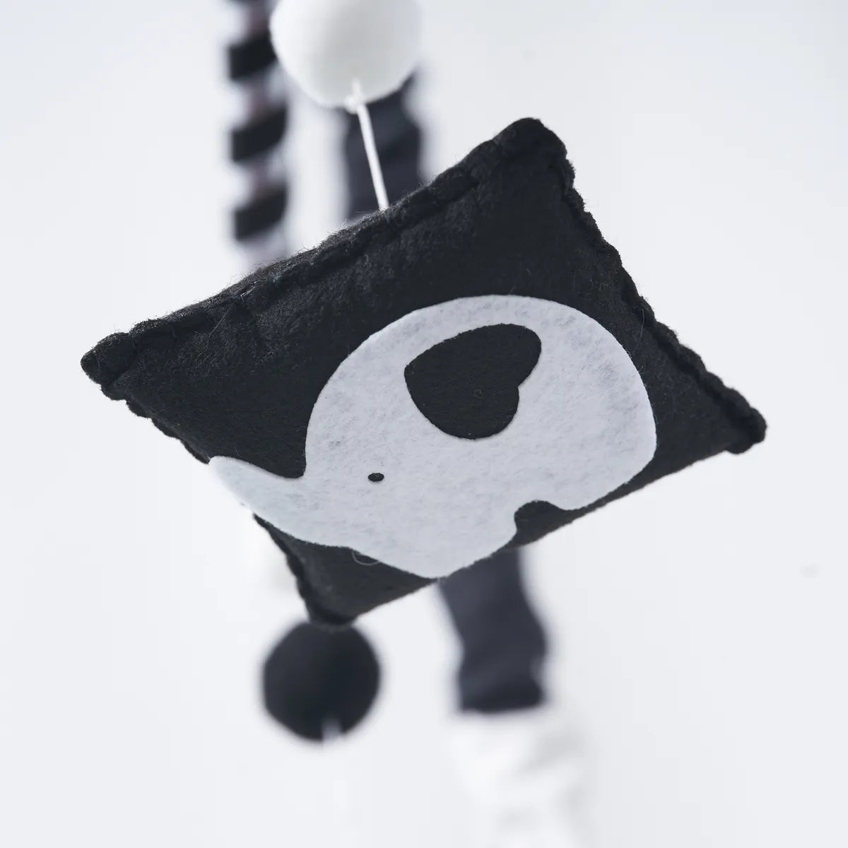 Close-up of a black-and-white felt animal on the Animal mobile
