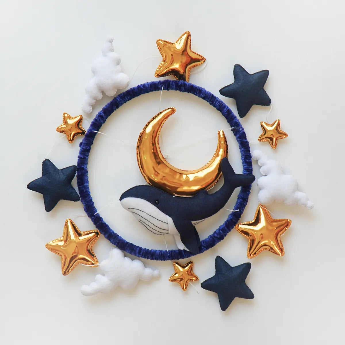 Ocean Whale mobile seen from above showing the navy, white and gold felt pieces around the hoop