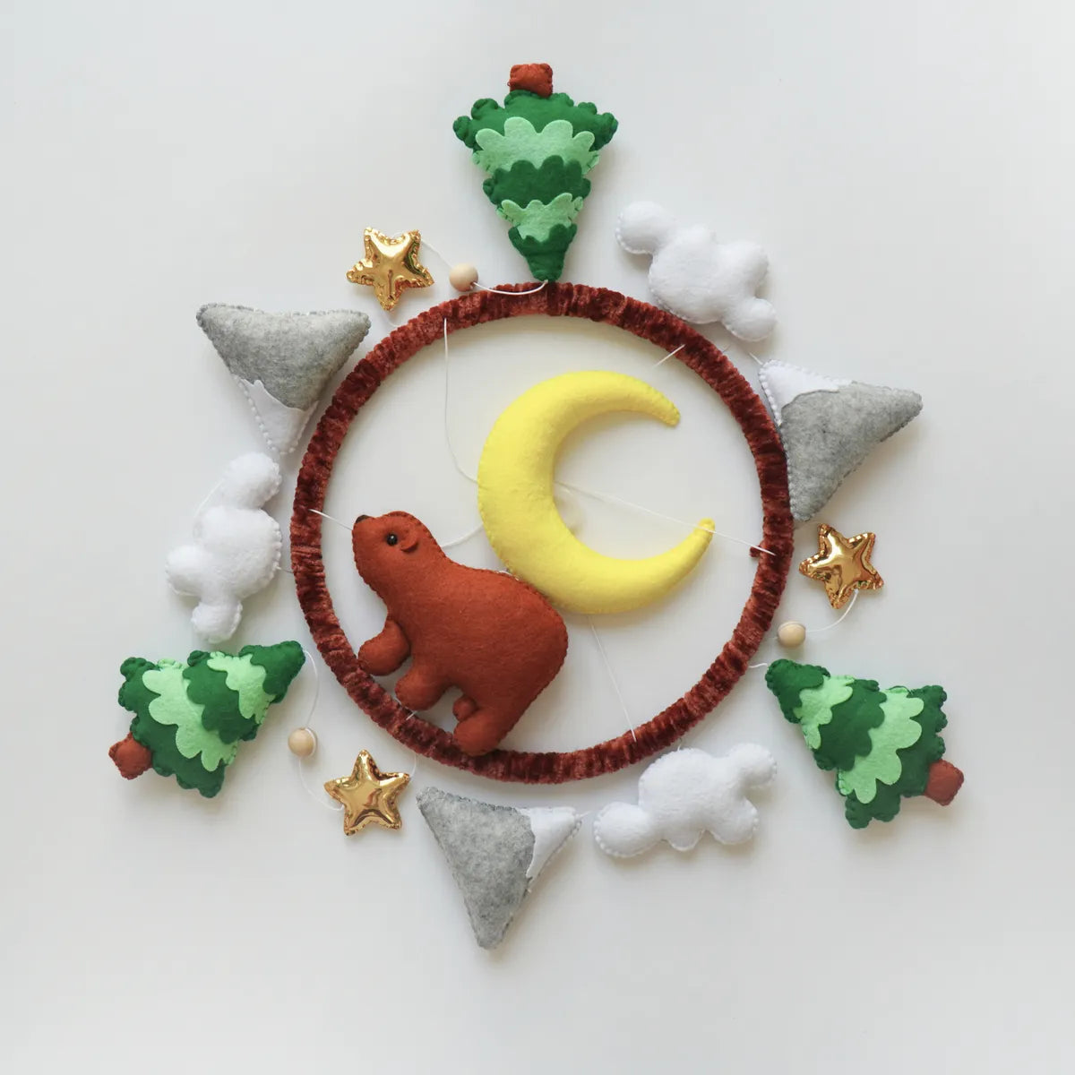 Woodland Bear mobile seen from above showing the rust, forest green, warm gray and yellow felt pieces