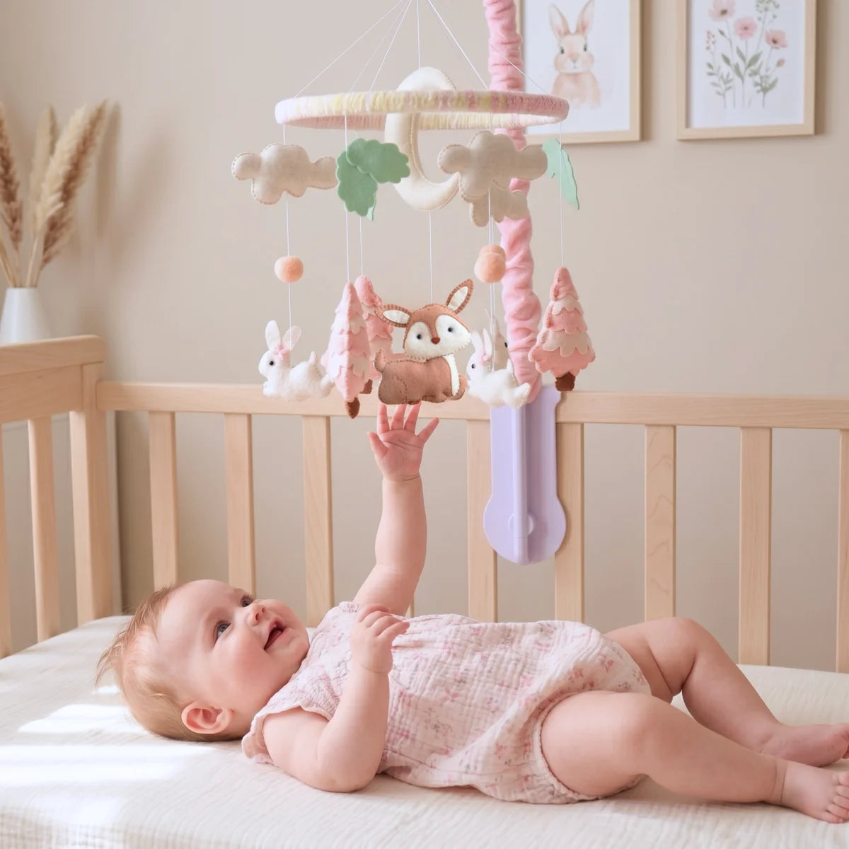 Baby in a crib reaching up toward the Pink Woodland Deer felt mobile