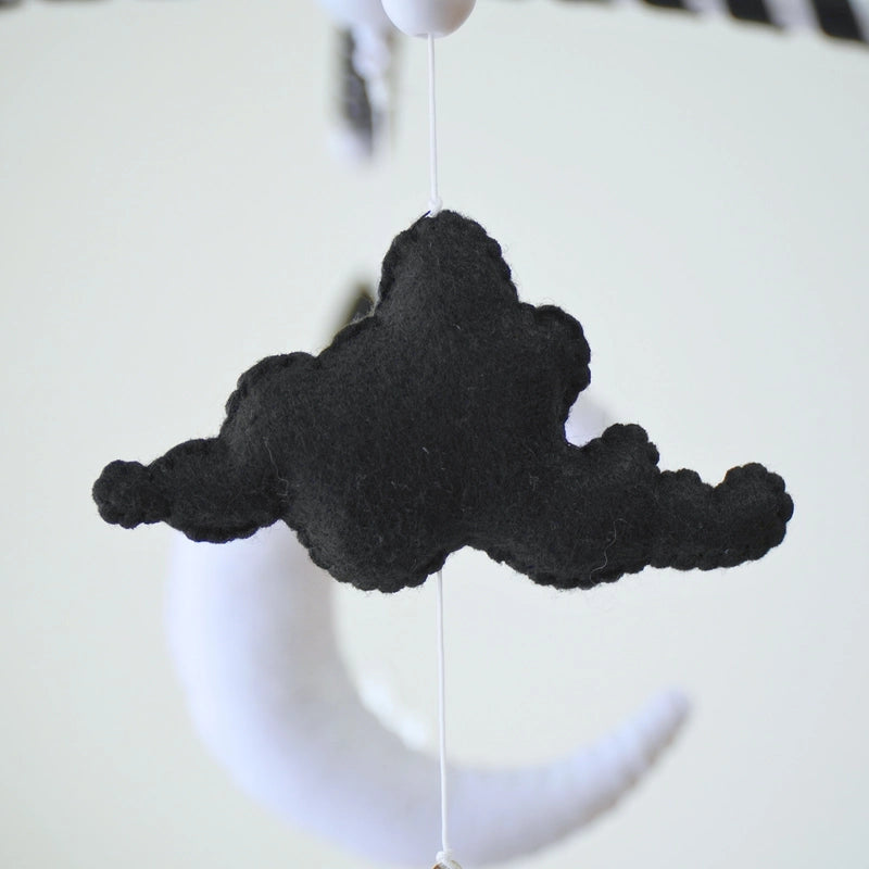 Black felt cloud and white moon plush hanging from Tinitigies baby crib mobile
