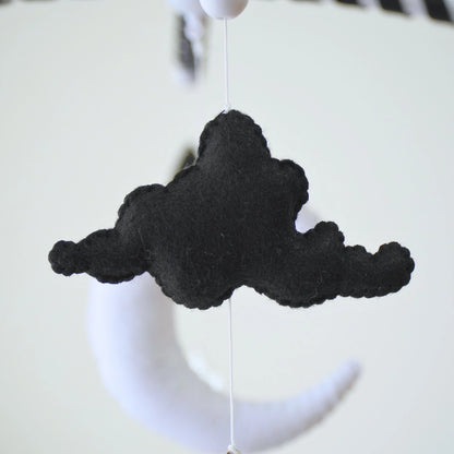 Black felt cloud and white moon plush hanging from Tinitigies baby crib mobile
