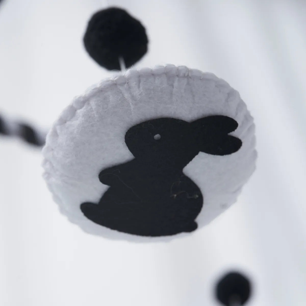 Close-up of the black-and-white felt rabbit on the Animal mobile
