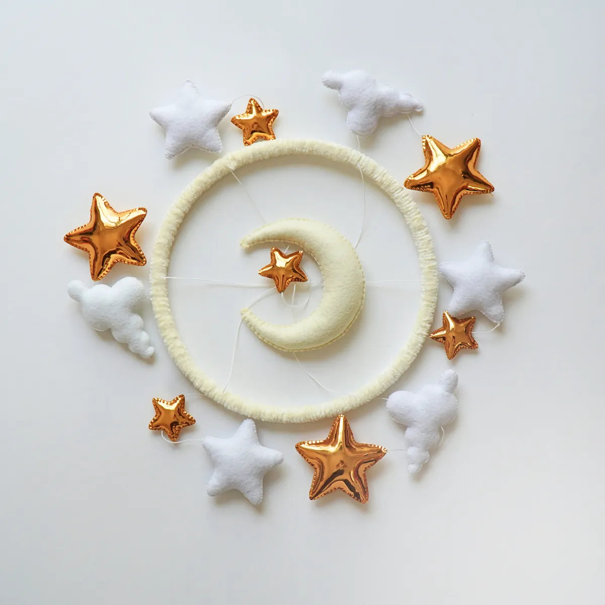 Moon & Stars mobile seen from above showing the white, cream and gold felt pieces