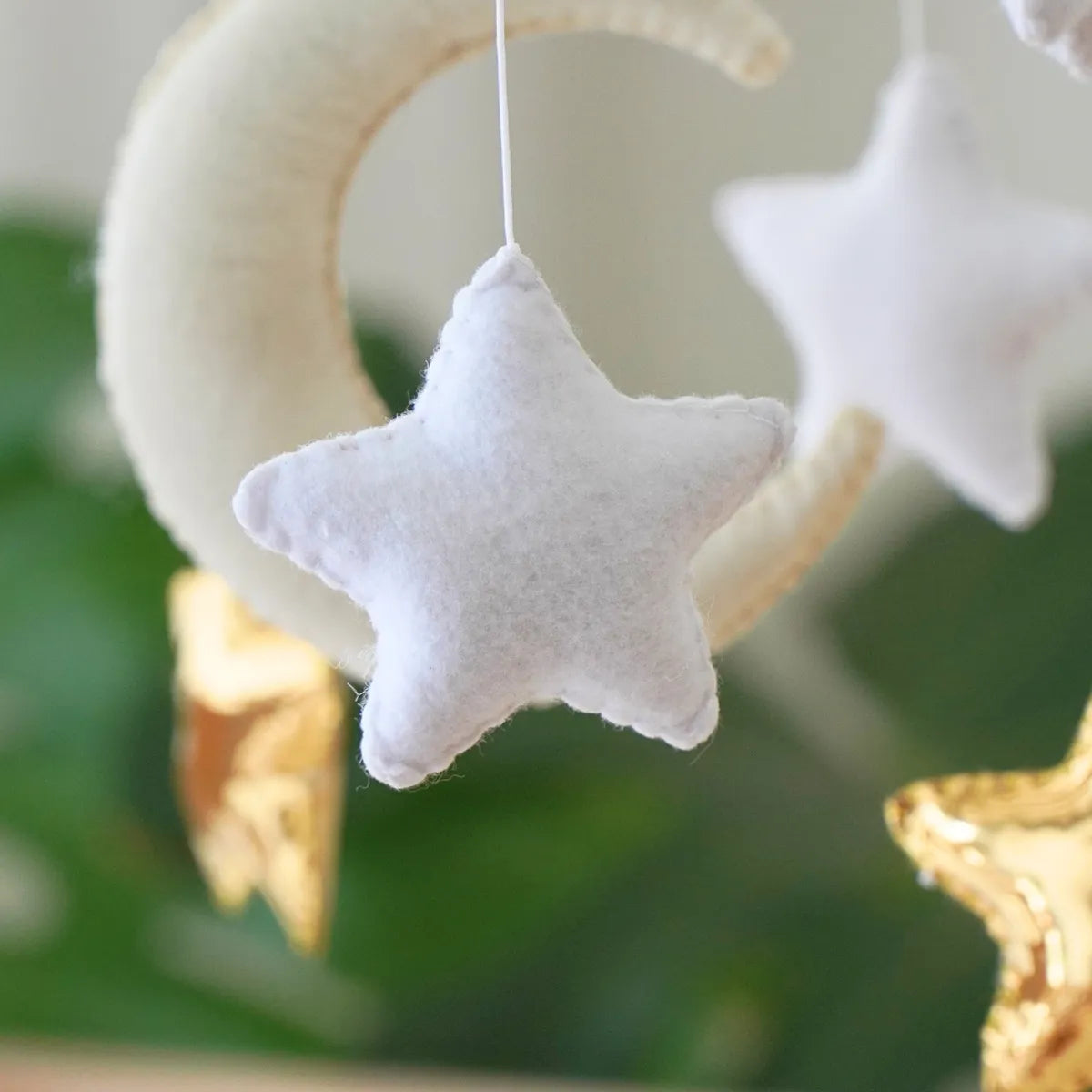 Close-up of a white felt star and gold-foil star on the Moon & Stars mobile