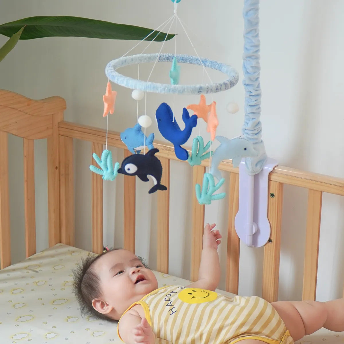 Baby lying in a crib looking up at the Ocean Creatures felt mobile