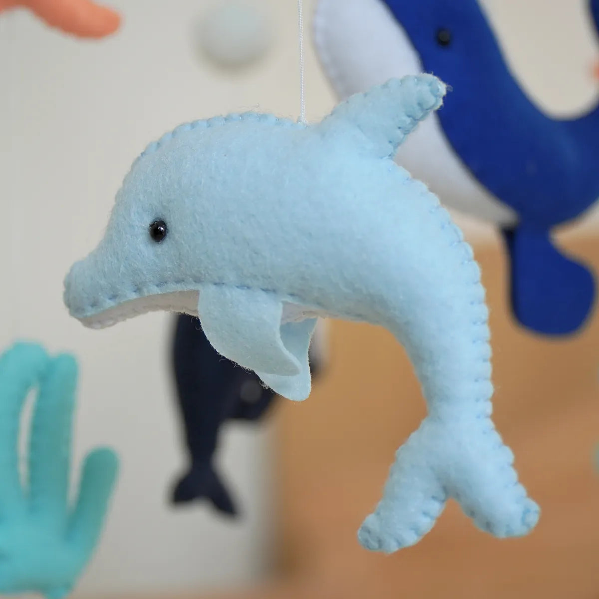Close-up of a hand-stitched light blue felt dolphin on the Ocean Creatures mobile
